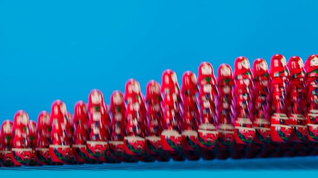 Row of Red Matryoshka Nesting Dolls on Blue Studio Background