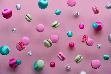 Levitation of macaroons, creative food concept. Bold vibrant pink, mint green and magenta colors. Flying tasty macaroons, mirror disco balls and decorative metallic balls on pink paper background.