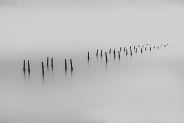 Minimalistisch, beeldende kunst, zwart-wit landschap, oude pier blijft in een wateroppervlak