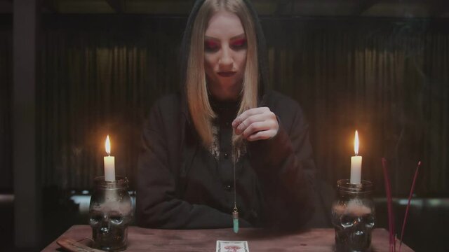 Fortune teller tarot reader uses a blue magic crystal and tarot caard in future telling ritual