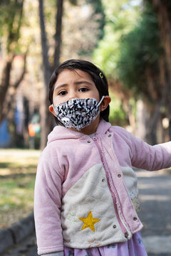 Portrait of a little latin girl in the park wearing a protective mask because of covid19 pandemic