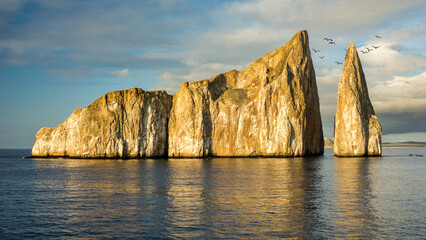 Sunrise glow shines on a unique rocky structure in the ocean creating vibrant reflections in the...