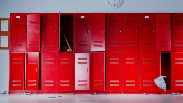 Red lockers in empty school hallway with paper flying
