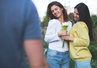 Young happy people man gives a flowers to his woman