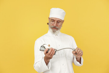 Smiling medical doctor with pressure gauge. Isolated over yellow background.