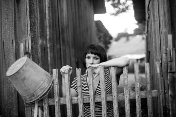 Portrait of woman standing near a wooden fence. Black and white photo.