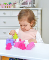 Cute adorable baby girl playing with colorful plastic bricks. Toddler Having Fun with educational toys. Kid building  something from colorful blocks. Early development concept.