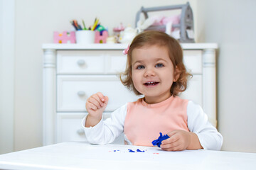 Cute adorable baby girl having fun with colorful modeling clay in kindergarten. Toddler molding at home. Cheerful child play with plasticine or dough. Having Fun and learn with educational toys.