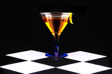 Cocktail in a blue stemmed glass on black and white checkerboard tile