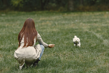 Fototapeta premium Woman in a brown coat. Lady with a labrador. Friends are having fun outside.