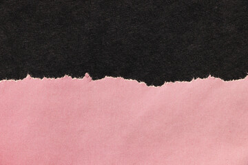 Ragged edges of pink paper on black surface. Empty background.	