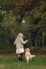 Mother and her daughter playing with dog. Family in autumn park. Pet, domestic animal and lifestyle concept. Autumn time.
