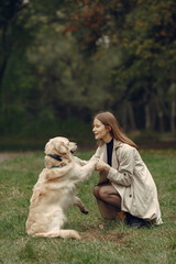 Woman in a brown coat. Lady with a labrador. Friends are having fun outside.