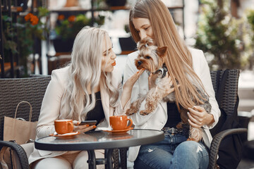 Ladies drinks a coffee. Women sitting at the table. Friends with a cute dog.