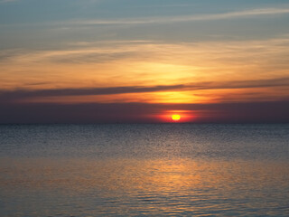 Fototapeta premium The sun is setting on the beach and the calm waters are beautiful.