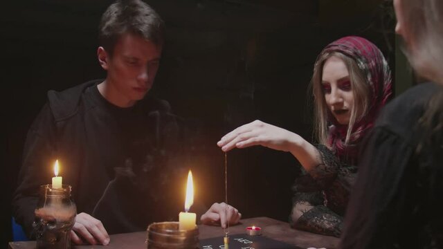 Witch female fortune teller tries to speak with ghost. Two women and one man uses Ouija Board Spirit Game