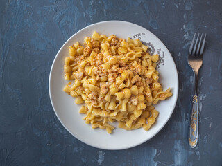 Pasta with minced chicken on a gray round plate for a hearty breakfast
