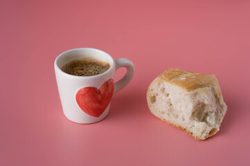 Cup espresso and baguette on pink background.