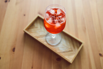 orange spritz cocktail in tall glass on wooden table with golden light shinining from nearby window,