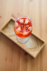 orange spritz cocktail in tall glass on wooden table with golden light shinining from nearby window,