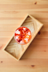 orange spritz cocktail in tall glass on wooden table with golden light shinining from nearby window,