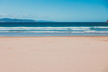 pristine wild landscape at Clifton Beach in Tasmania, Australia with wavy blue ocean and golden sand next to a rugged coastline