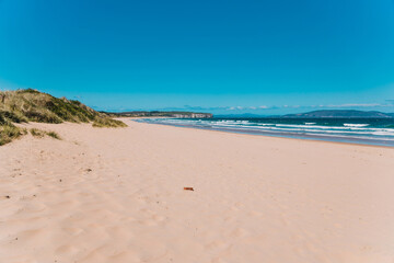 Fototapeta na wymiar pristine wild landscape at Clifton Beach in Tasmania, Australia with wavy blue ocean and golden sand next to a rugged coastline