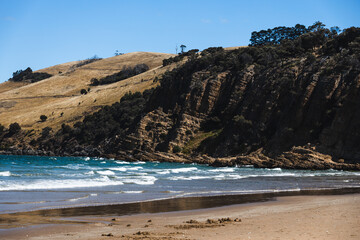 pristine wild landscape at Clifton Beach in Tasmania, Australia with wavy blue ocean and golden sand next to a rugged coastline
