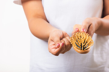 Obraz premium Asian woman unhappy weak hair problem her hold hairbrush with damaged long loss hair in the comb brush she pulls loss hair from the brush, isolated on white background, Medicine health care concept