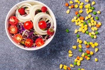Top view of the healthy colorful salad bowl with tomatoes fresh mixed leaves vegetable in a dish on cement stone table background, Health salad snack diet food weight loss concept