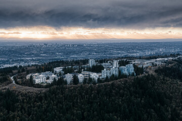 Striking Aerial view of Burnaby Mountain during a dramatic cloudy sunset. Taken in Vancouver, British Columbia, Canada.