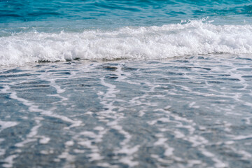 White foamy waves on sandy beach closeup. Seaside on sunny summer day. Summer vacation time concept.