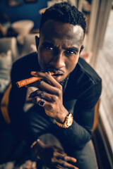portrait of african american man holding cigar on hand in coffee shop