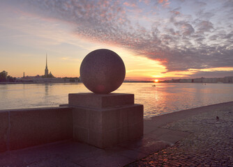 Sunrise over the Neva river. View of the Peter and Paul Cathedral and the Palace embankment from The spit of Vasilievsky island. Granite parapet with a stone ball