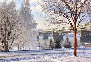 Michael's embankment in winter. Oktyabrsky bridge over the Ob river, birch trees in the snow, covered with frost