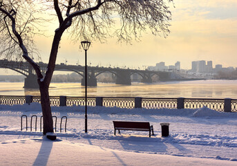 Fototapeta na wymiar Michael's embankment in winter. Oktyabrsky bridge over the Ob river leads to the Gorsky district