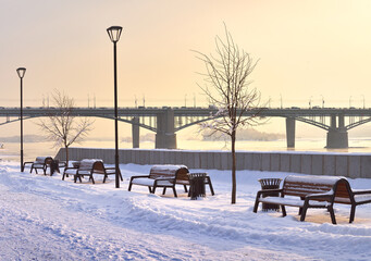 Michael's embankment in winter. Benches along the pedestrian alley, Oktyabrsky bridge in the distance
