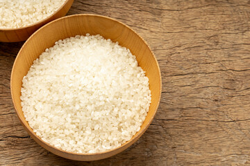 Japanese rice in wooden bowl on texture of wood background