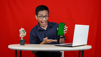 Young asian business man pointing handphone green screen isolated red background