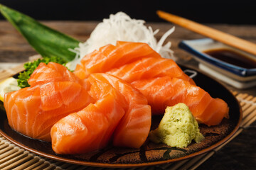 Sashimi, Salmon, Japanese food chopsticks and wasabi on the wood table.