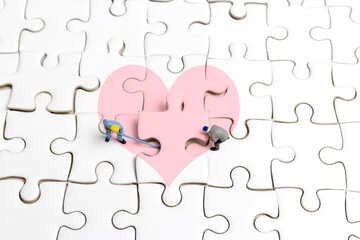 Miniature people the team is working on a puzzle piece with a heart shape  , valentines day concept