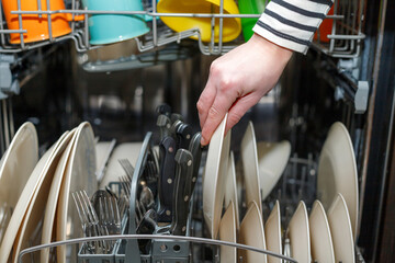 Woman loading or uploading dishwasher machine