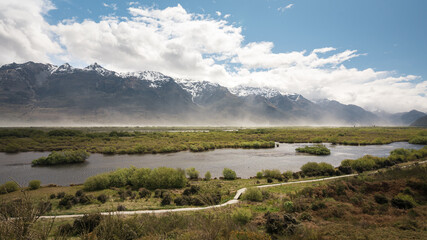 Fototapeta na wymiar Lagoon in Glenorchy with snowy peaks behind and full of dust in the wind. New Zealand, South Island