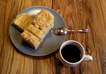 a cut piece of cake on a saucer and a cup of coffee standing nearby