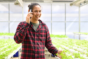 Asian young man farmer using smartphone in vegetable hydroponics farm