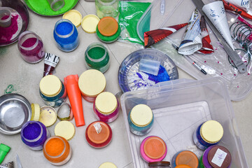 variety of rangoli colors on floor in small jars and some in plate to make rangoli on entrance of the door