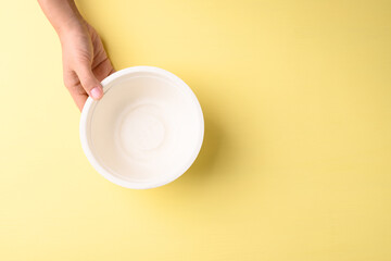 Hand holding bowl(Biodegradable, Compostable, Disposable or Eco friendly bowl) on yellow background, Sustainable concept