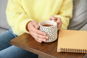 Woman with cup of tea resting on sofa at home