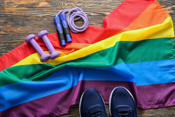 Sports equipment and rainbow LGBT flag on wooden background