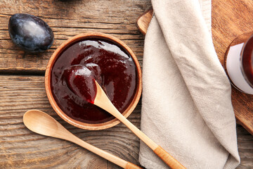 Bowl with delicious homemade plum jam on wooden background